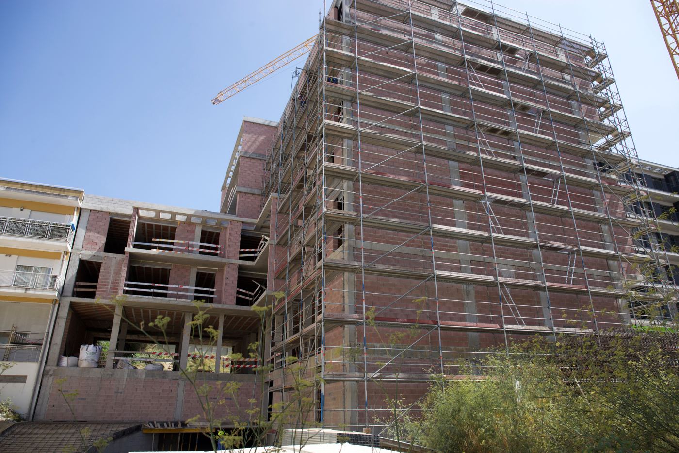 Edifício residencial em construção com andaimes e grua